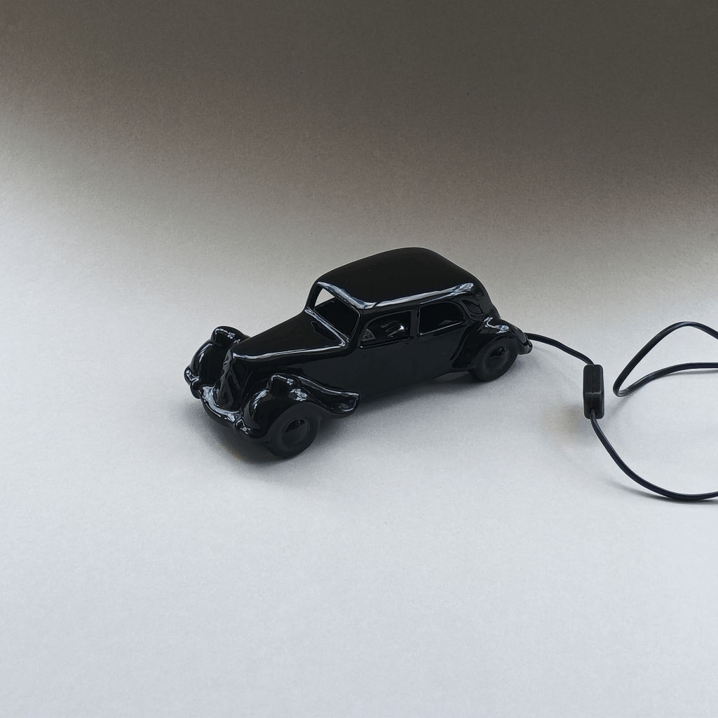 Lampe éteinte en céramique noire design des années 80, en forme de voiture ancienne, une "Traction" vue du coté gauche
