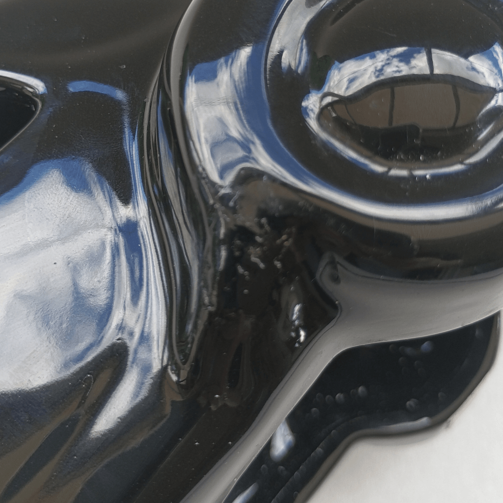 Gros plan sur restauration d'une "aile" d'une lampe en céramique noire en forme de "Traction" des années 80
