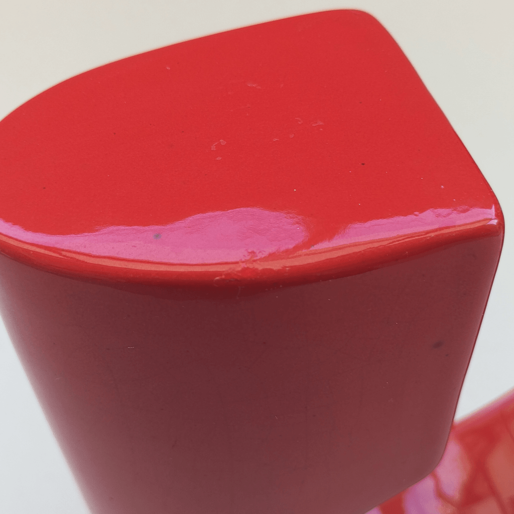 Gros plan sur une restauration d'un vase en céramique rouge design des années 70/80