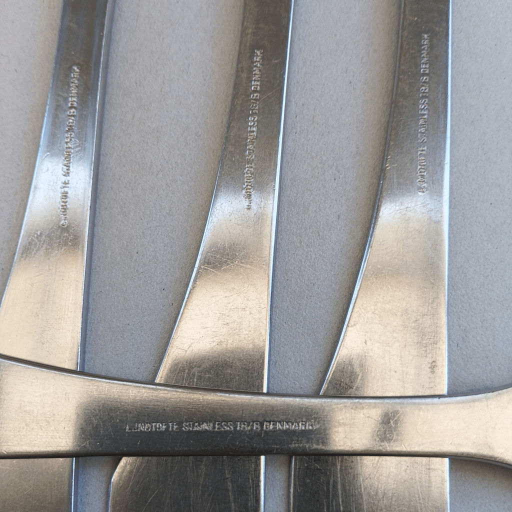 Gros plan sur la marque, la matière et le pays de fabrication gravés sur les manches des couverts "Easy" Lundtofte